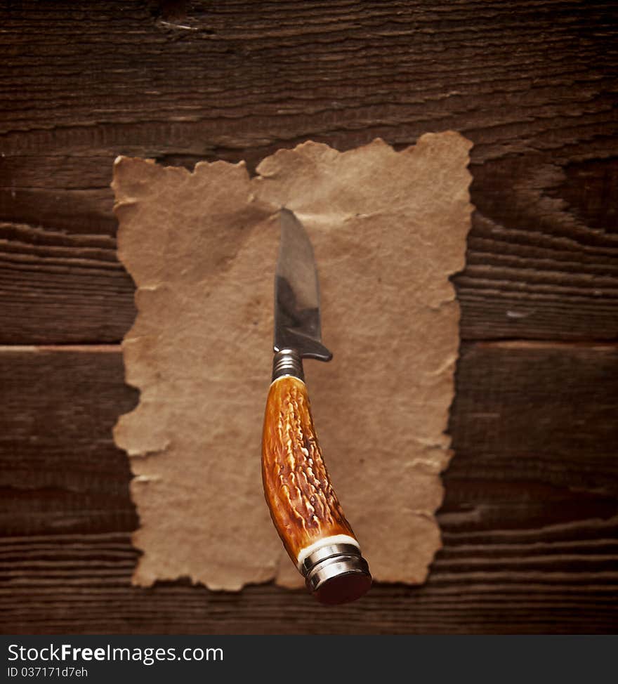 Old paper pinned to a wooden wall with a knife