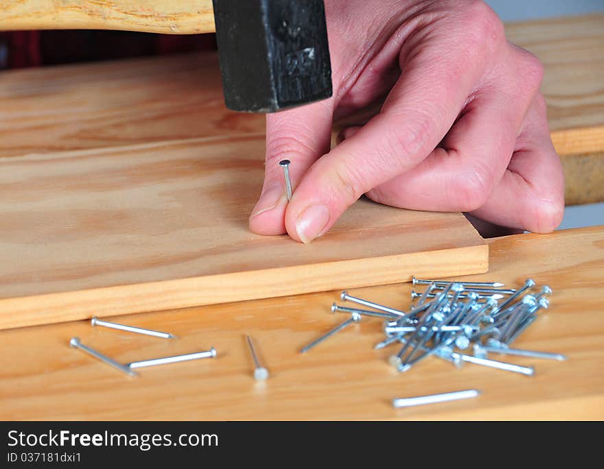 First plane of hands with hammer nailing a tip. First plane of hands with hammer nailing a tip