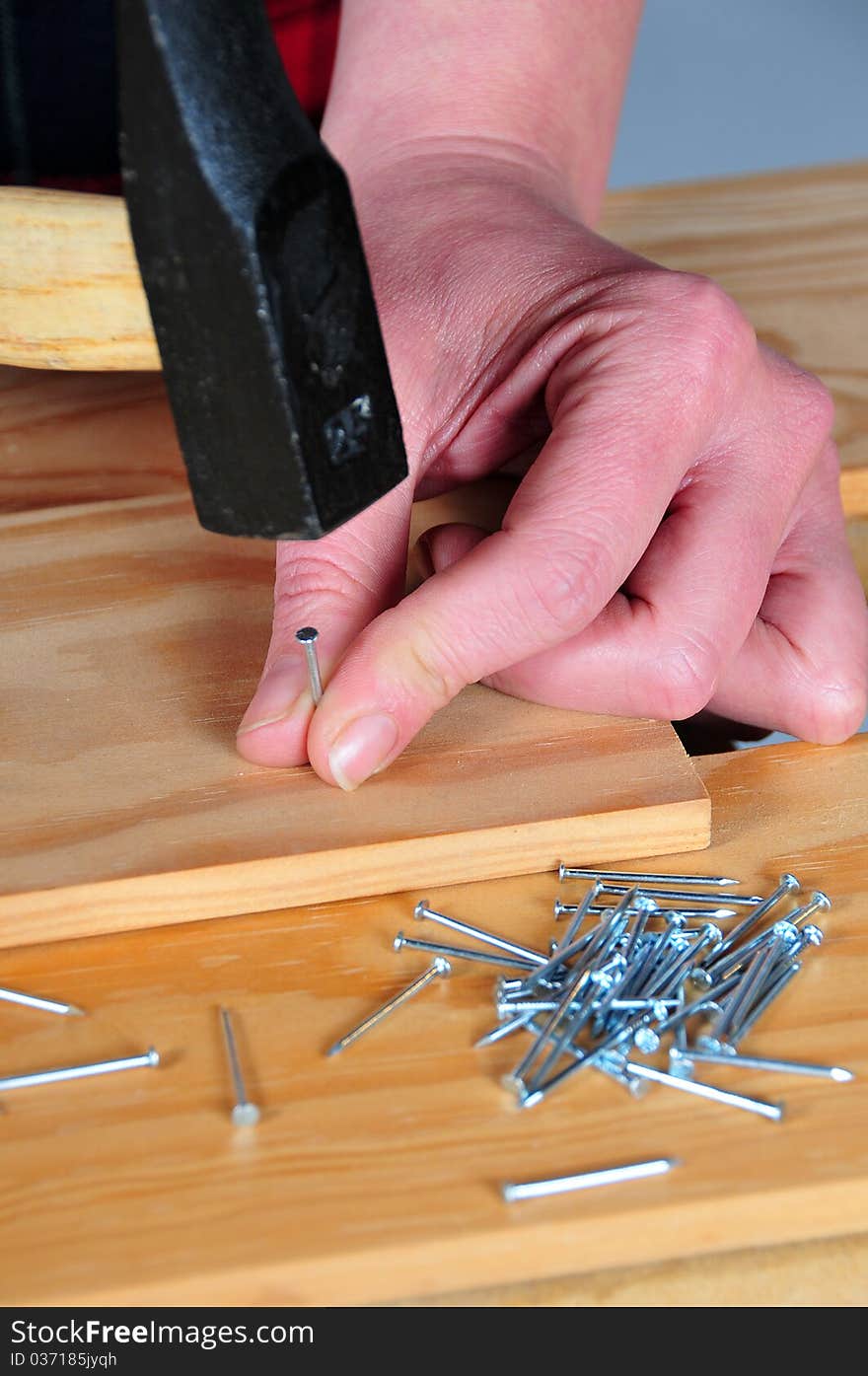 First plane of hands with hammer nailing a tip. First plane of hands with hammer nailing a tip