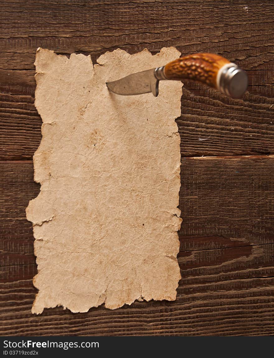 Old paper pinned to a wooden wall with a knife