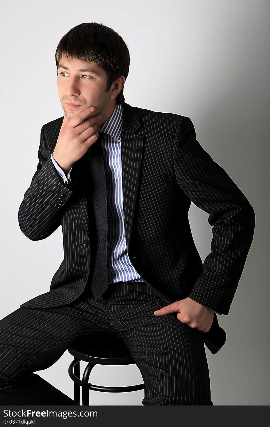 A young man in business suit sitting on a chair