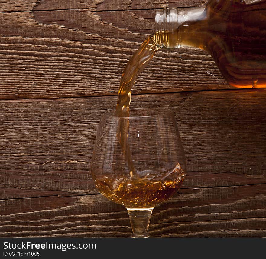 Cognac pour from a bottle in a glass