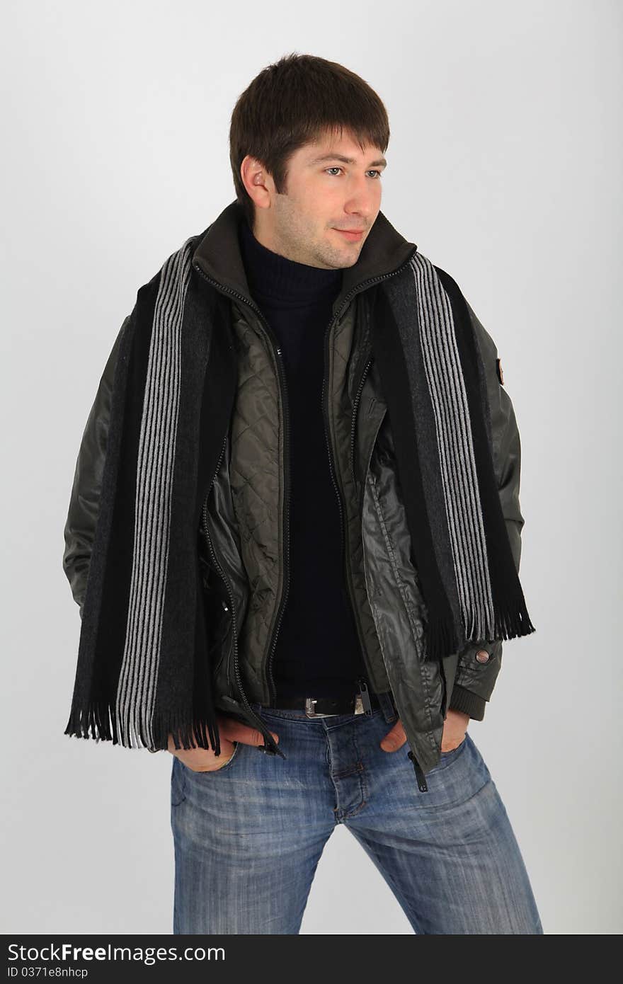 Young male in jeans and jacket with a scarf around his neck, posing