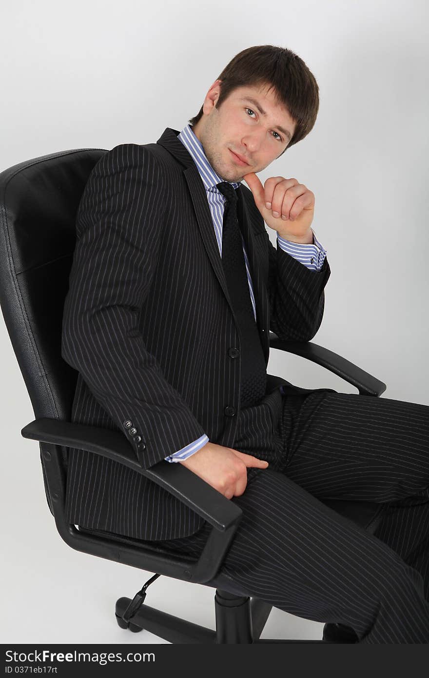 A young man in business suit sitting on a chair in a pensive pose