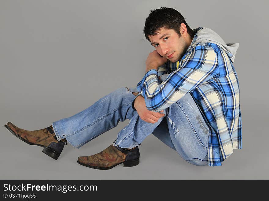 Man in jeans and a plaid shirt sitting on the floor