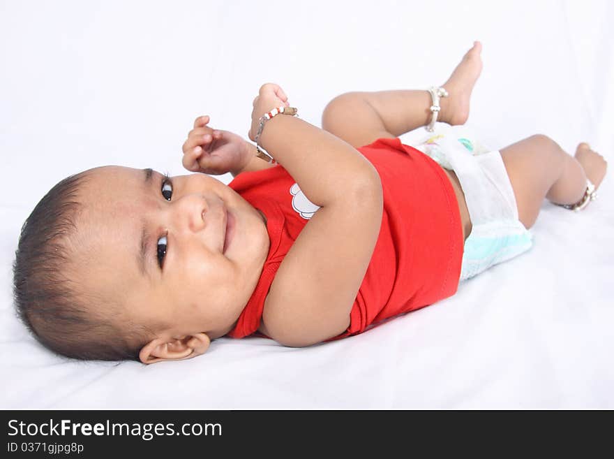 Smiling Indian Cute Baby lying on Bed