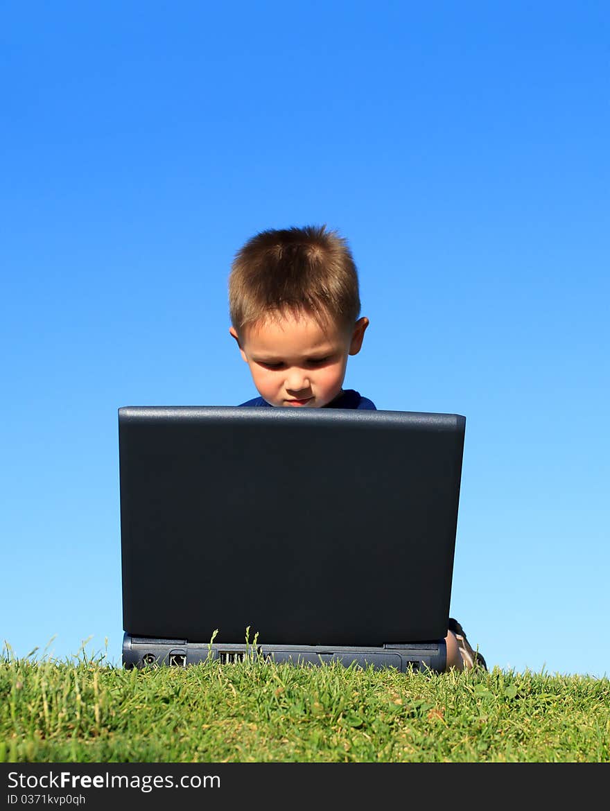 Little boy with laptop against blue sky