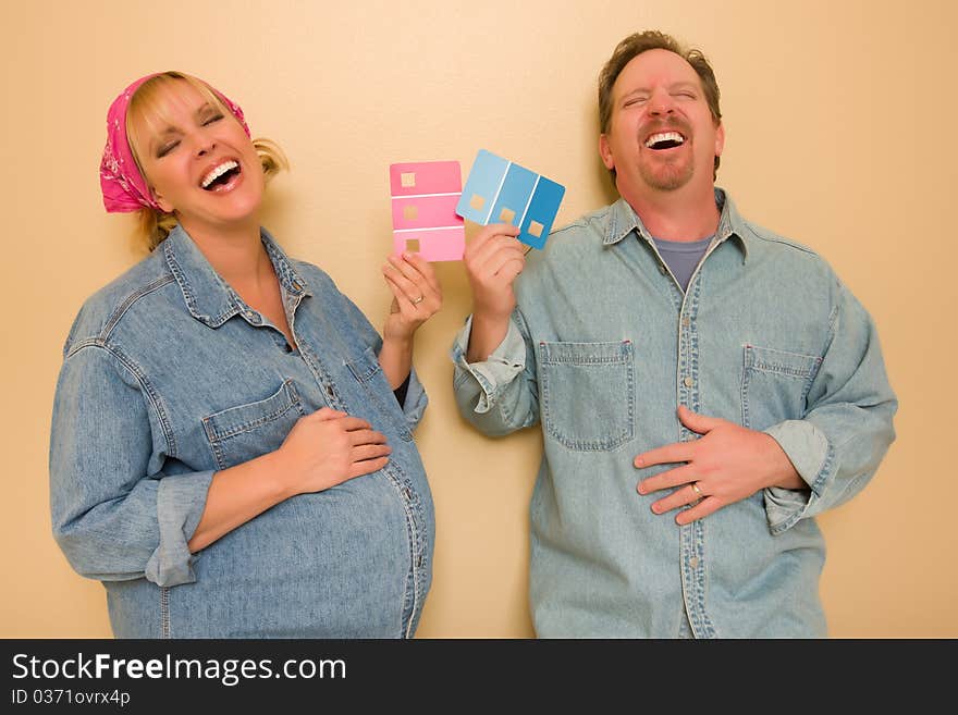 Laughing Man and Pregnant Woman Deciding on Pink or Blue Wall Paint with Swatches in Hand. Laughing Man and Pregnant Woman Deciding on Pink or Blue Wall Paint with Swatches in Hand.