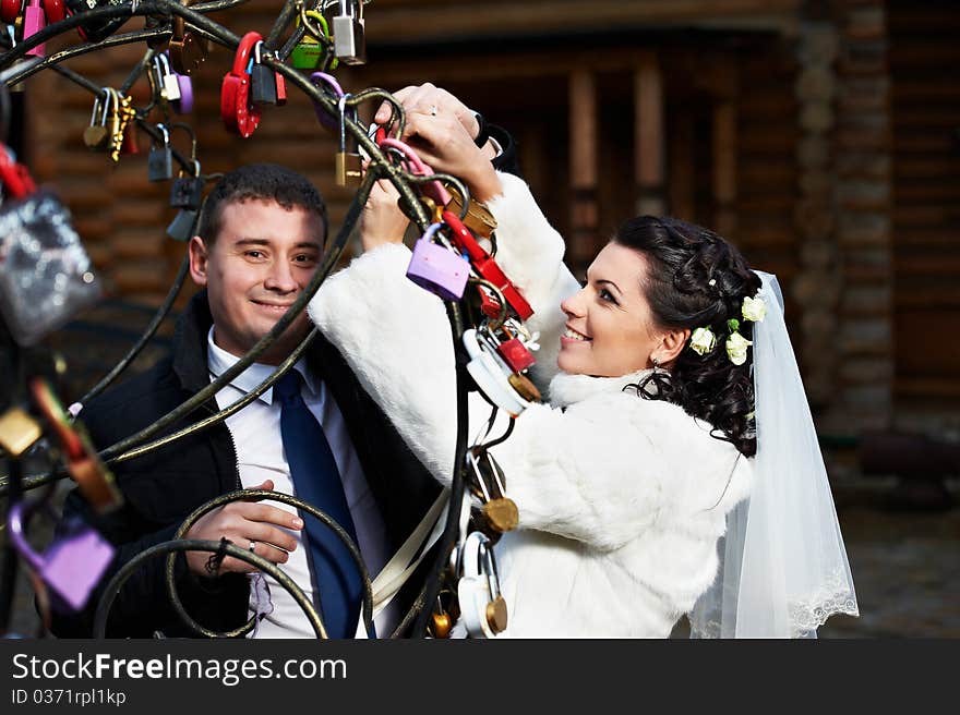 Happy bride and groom near metal tree with symbol lock at a wedding a walk in Moscow