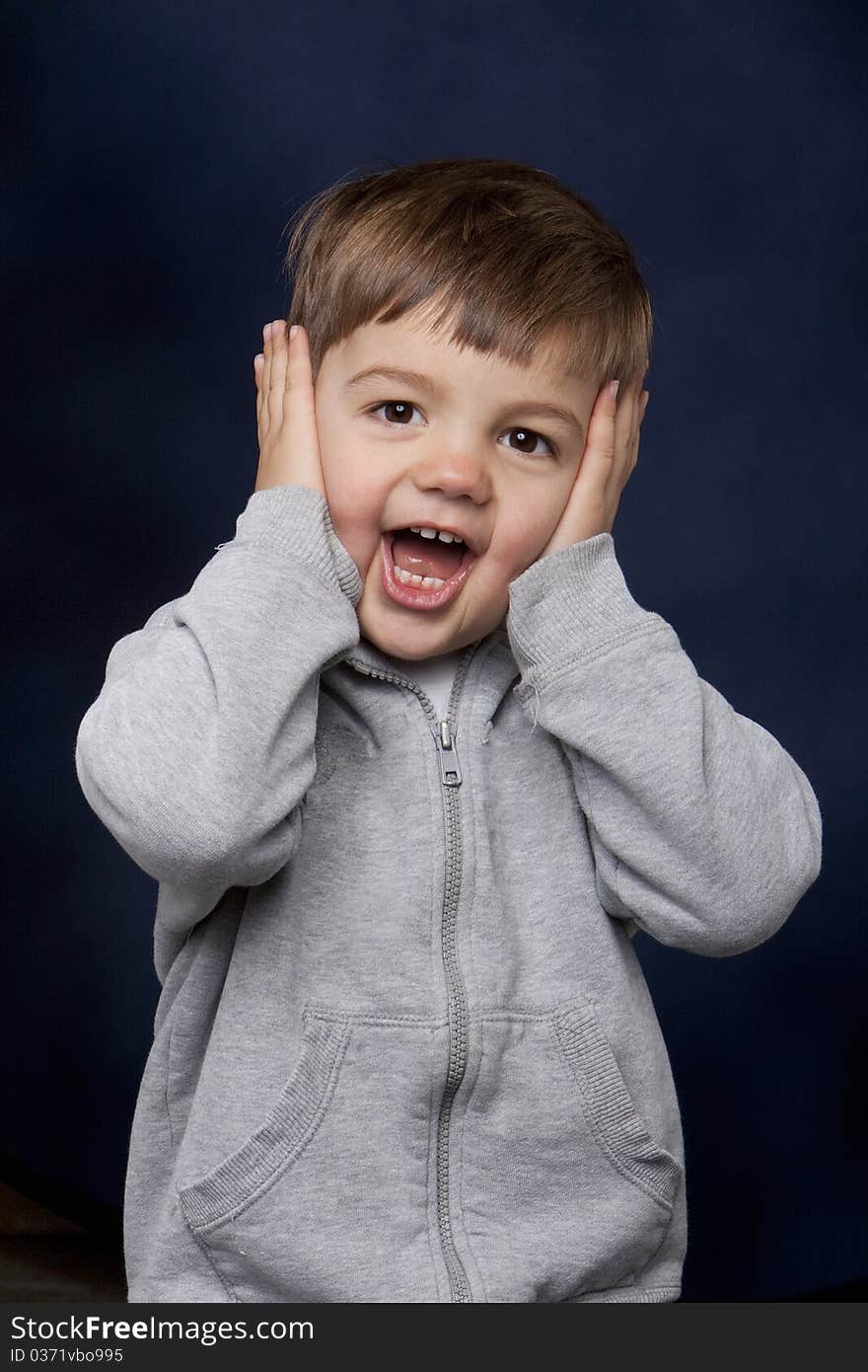 Toddler-aged boy with hands over his face and a surprised expression. Toddler-aged boy with hands over his face and a surprised expression.