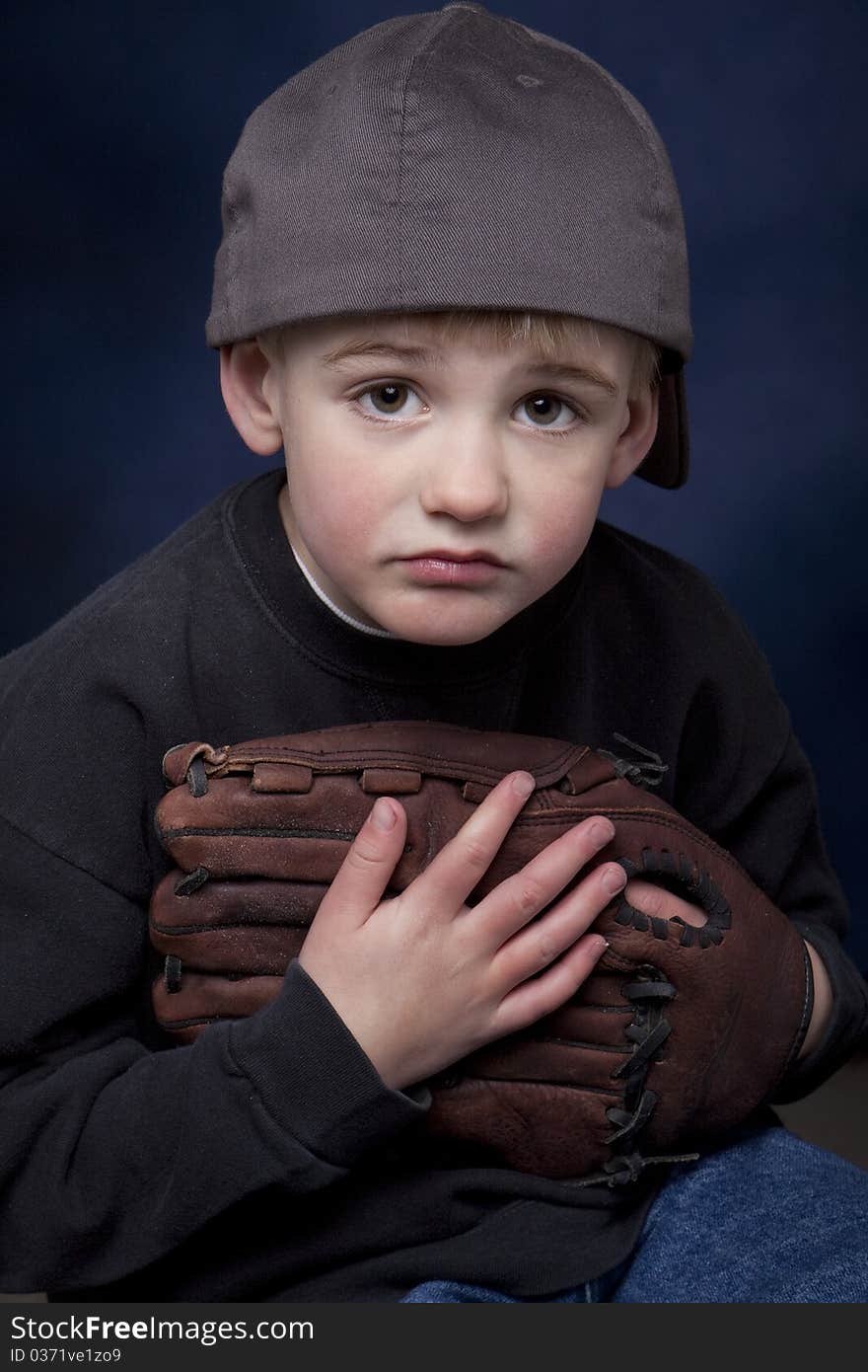 Young boy with a baseball hat and glove and a sad expression. Young boy with a baseball hat and glove and a sad expression.