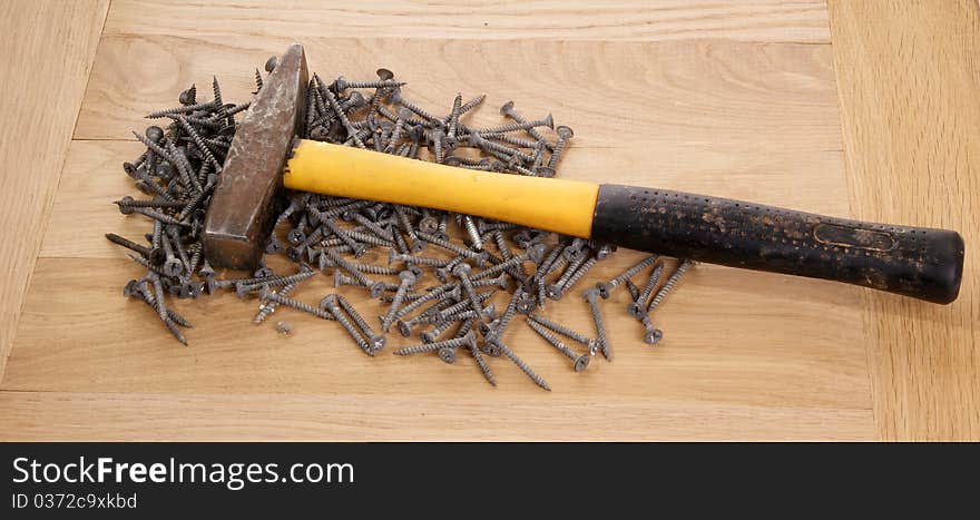 A pile of old screws and a hammer closeup to the background of the tree