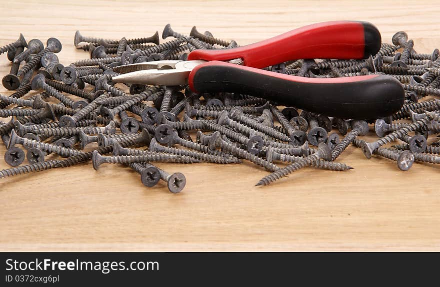 A pile of old screws and pliers closeup to the background of the tree