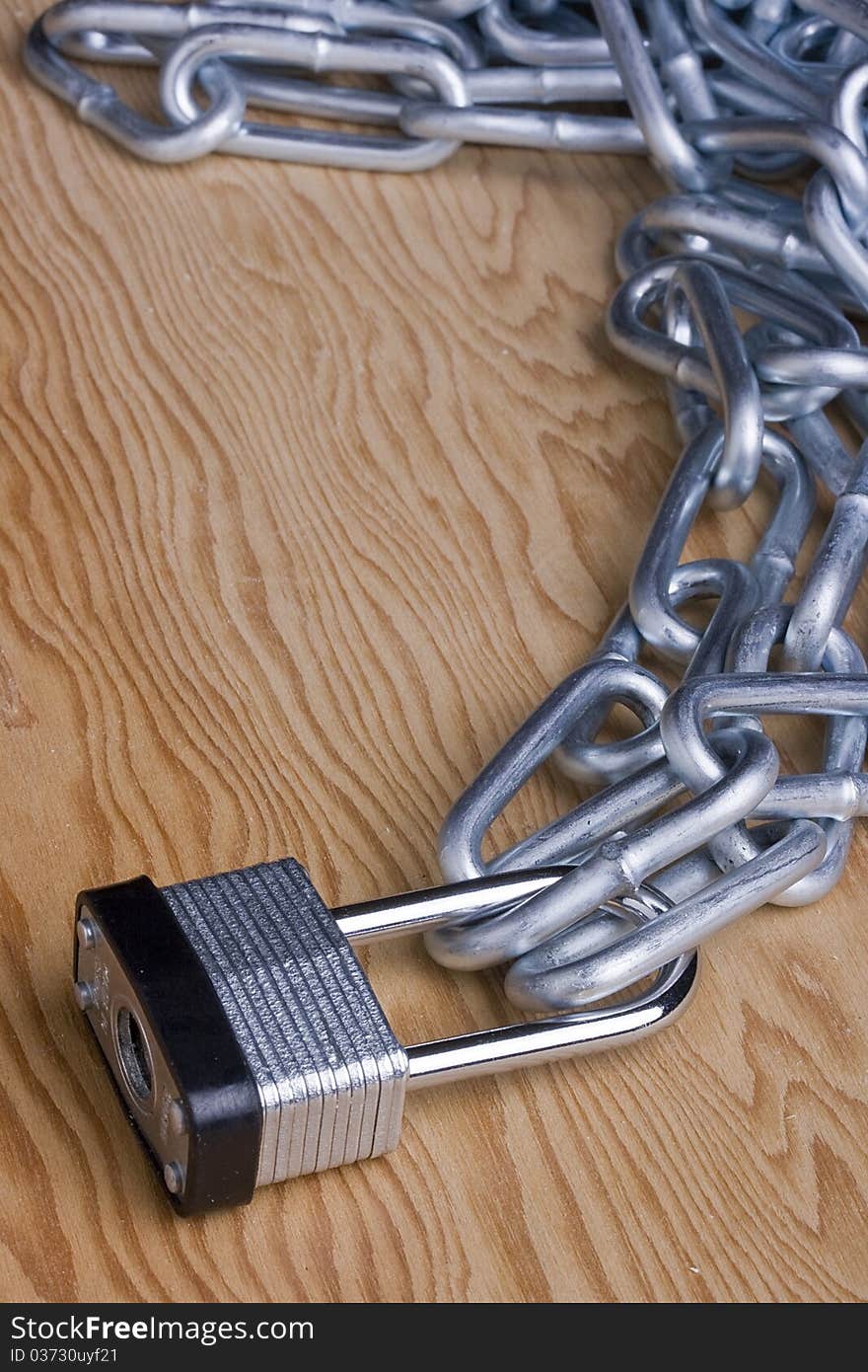 Metal lock and chain on a wooden background. Add your text to the background.