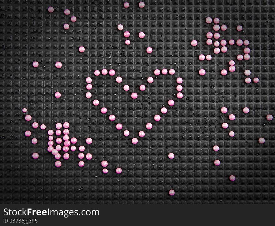 Heart shape made with candy on rubber black background