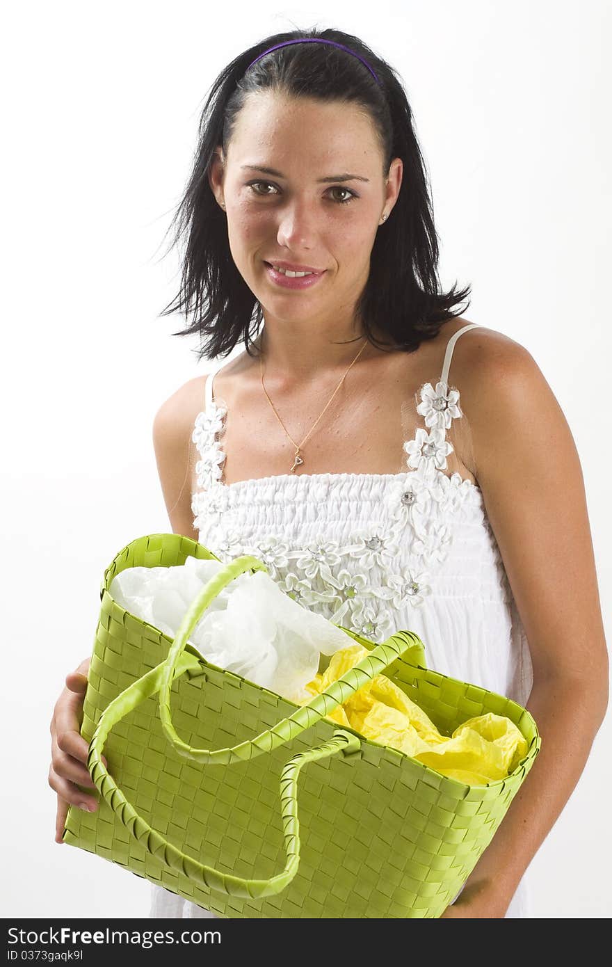 Young tanned healthy woman in a white summer cotton dress holding a green woven shopping bag. Young tanned healthy woman in a white summer cotton dress holding a green woven shopping bag