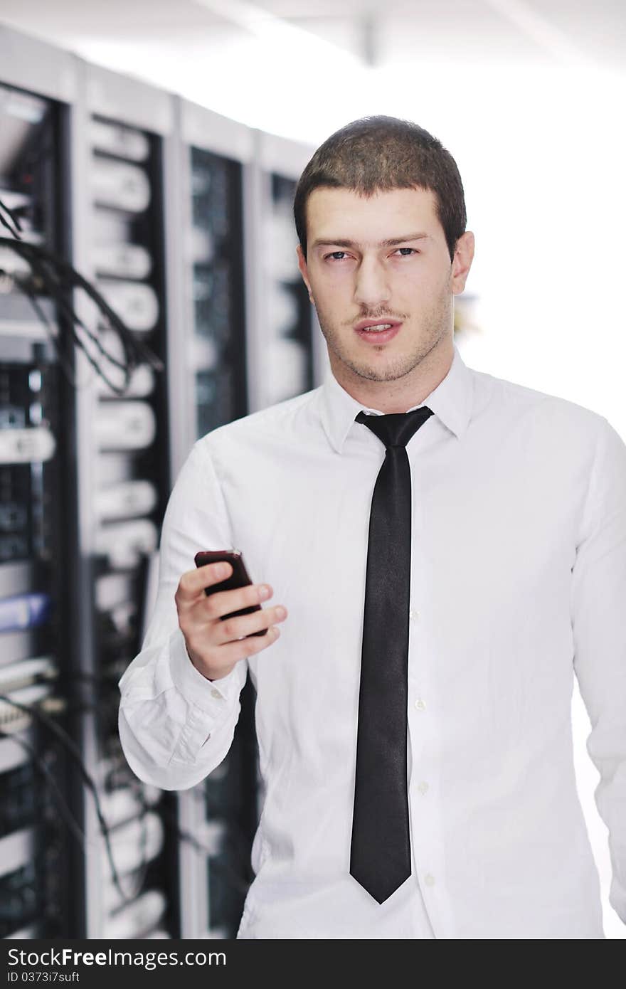 Young business man computer science engeneer talking by cellphone at network datacenter server room asking for help and fast solutions and services. Young business man computer science engeneer talking by cellphone at network datacenter server room asking for help and fast solutions and services