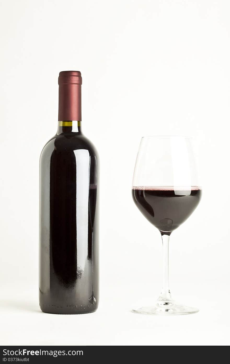 Glass of red wine and a bottle isolated over white background