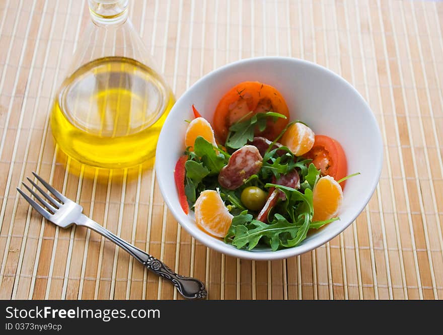 Salad greens, mandarin orange and salami in a white plate. Salad greens, mandarin orange and salami in a white plate.