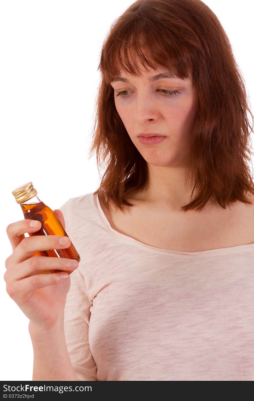 A young woman is critically looking at a bottle of hard liquor. A young woman is critically looking at a bottle of hard liquor