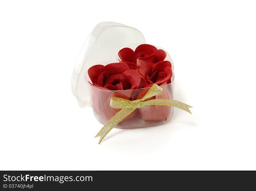 Buds of roses from a fabric in a transparent box are isolated on a white background