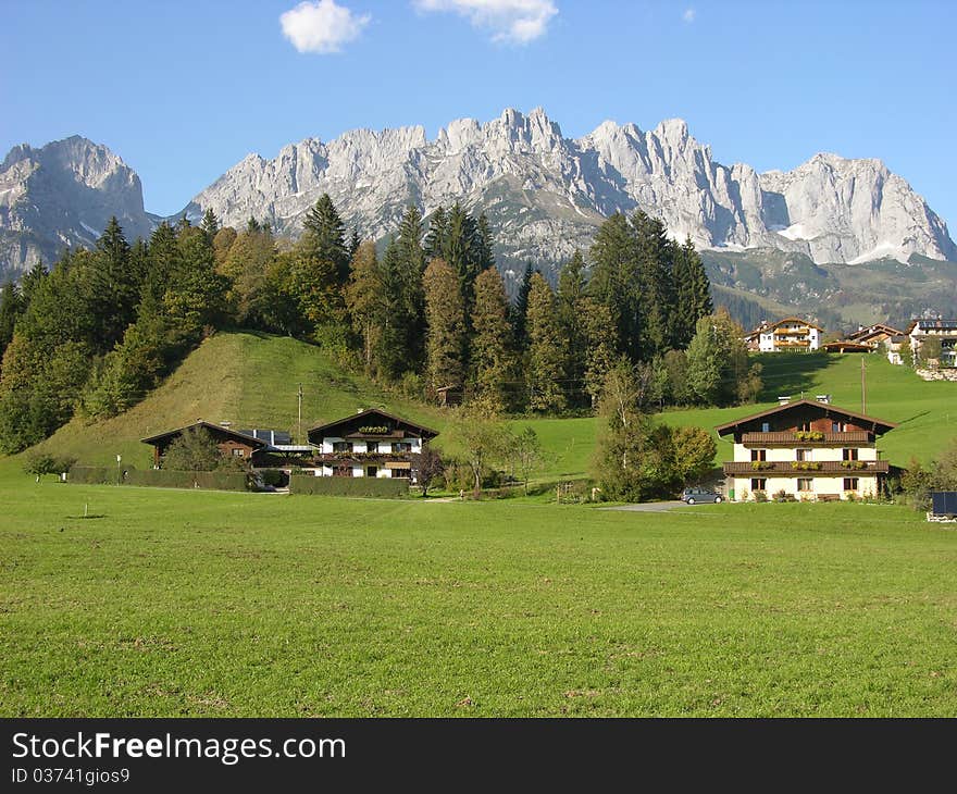 A peaceful alpine land with houses, pinewoods, rock and blue sky. A peaceful alpine land with houses, pinewoods, rock and blue sky.