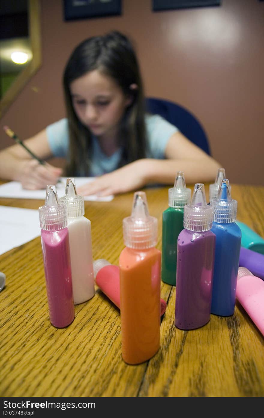 Colorful paint bottles with child drawing in background. Colorful paint bottles with child drawing in background