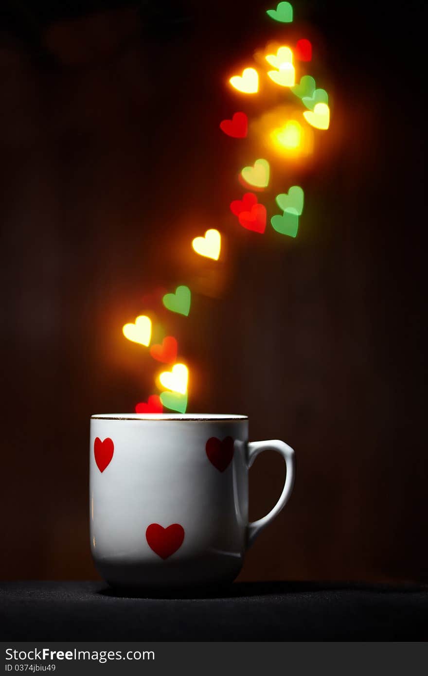 Mug emits steam of glowing hearts on dark background with copy space. Mug emits steam of glowing hearts on dark background with copy space