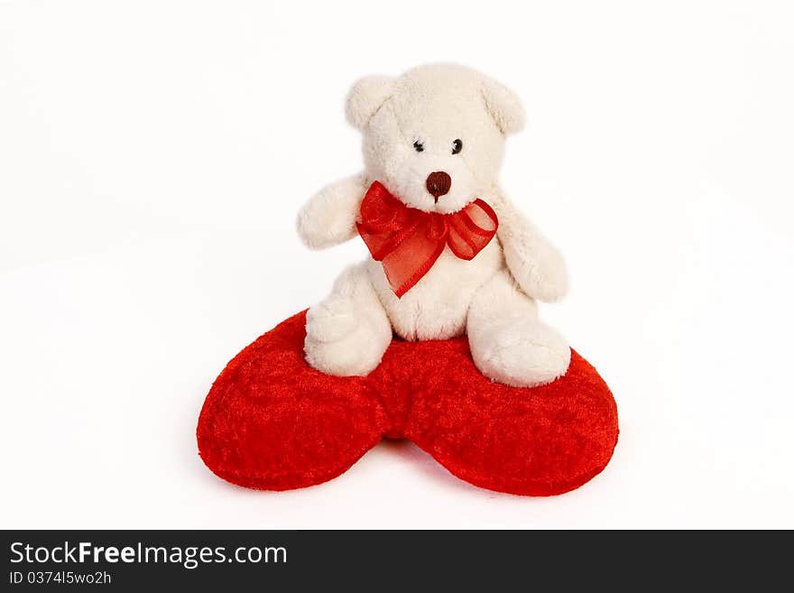 White Teddy Bear Sitting On A Heart Shaped Pillow