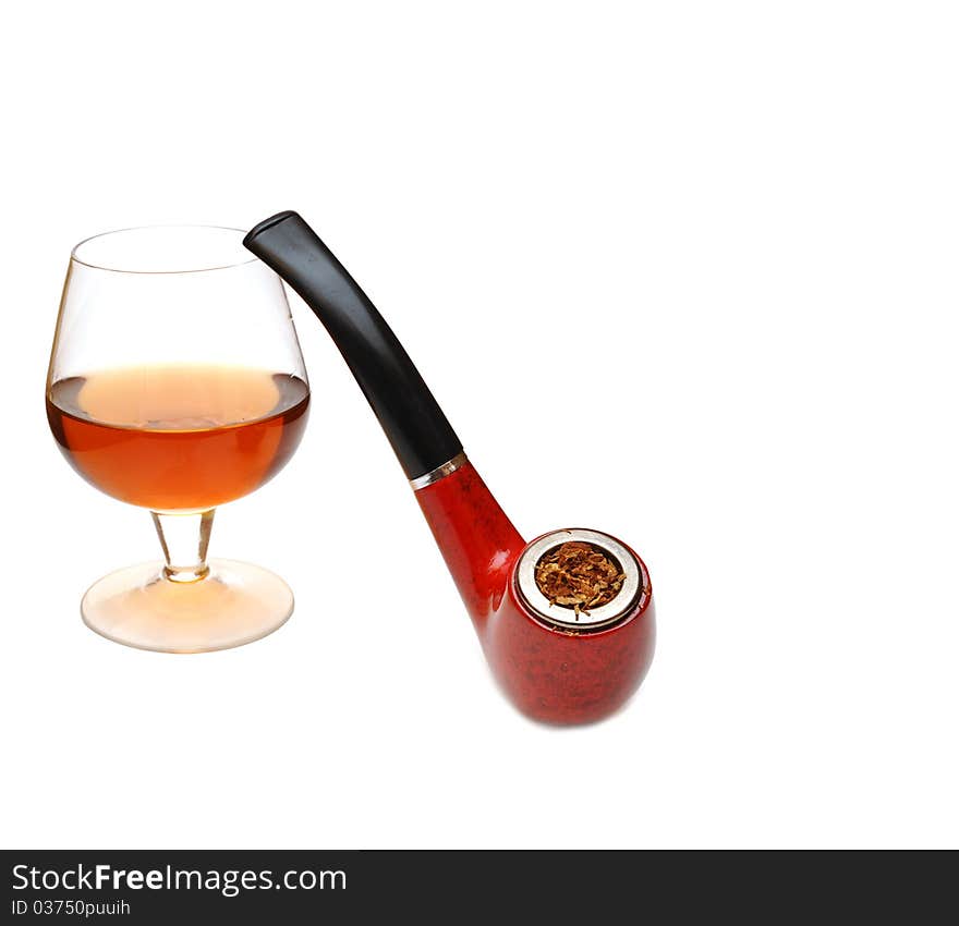 Pipe and glass of cognac on wood background. Pipe and glass of cognac on wood background