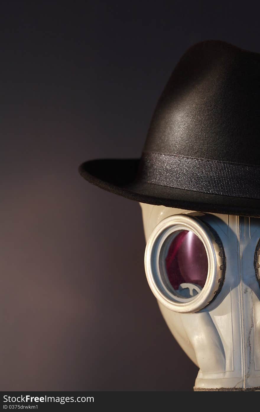 Gas mask with a felt hat closeup on dark background. Gas mask with a felt hat closeup on dark background