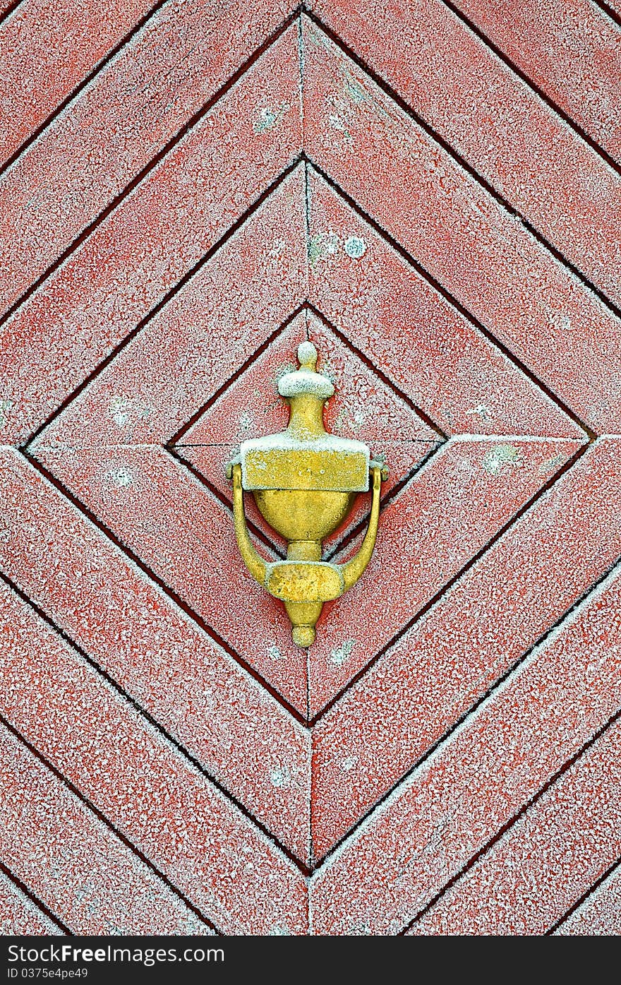Brass door knocker on a old red frosted door.