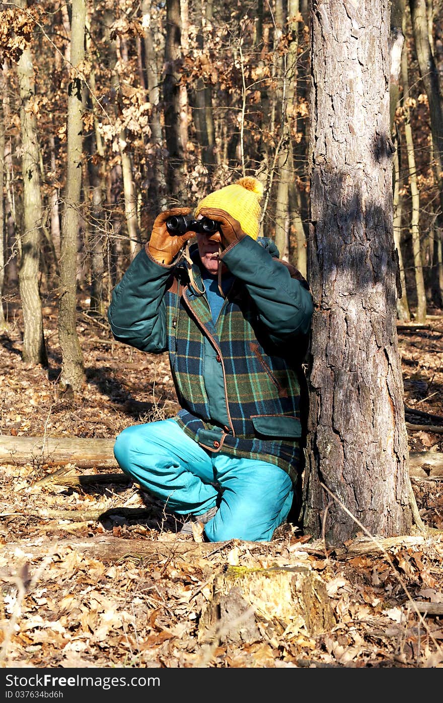 Senior man is watching the wildlife with binoculars in winter forest. Senior man is watching the wildlife with binoculars in winter forest