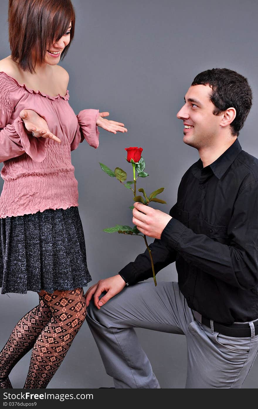 Happy beautiful teenage couple, a boy giving a rose to his girlfriend