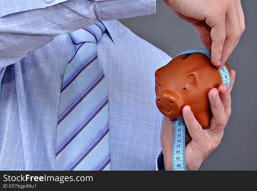 Business man with brown piggy bank and measure tape