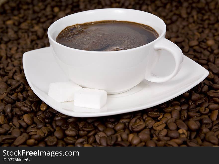 Cup with coffee on spilled grains of coffee