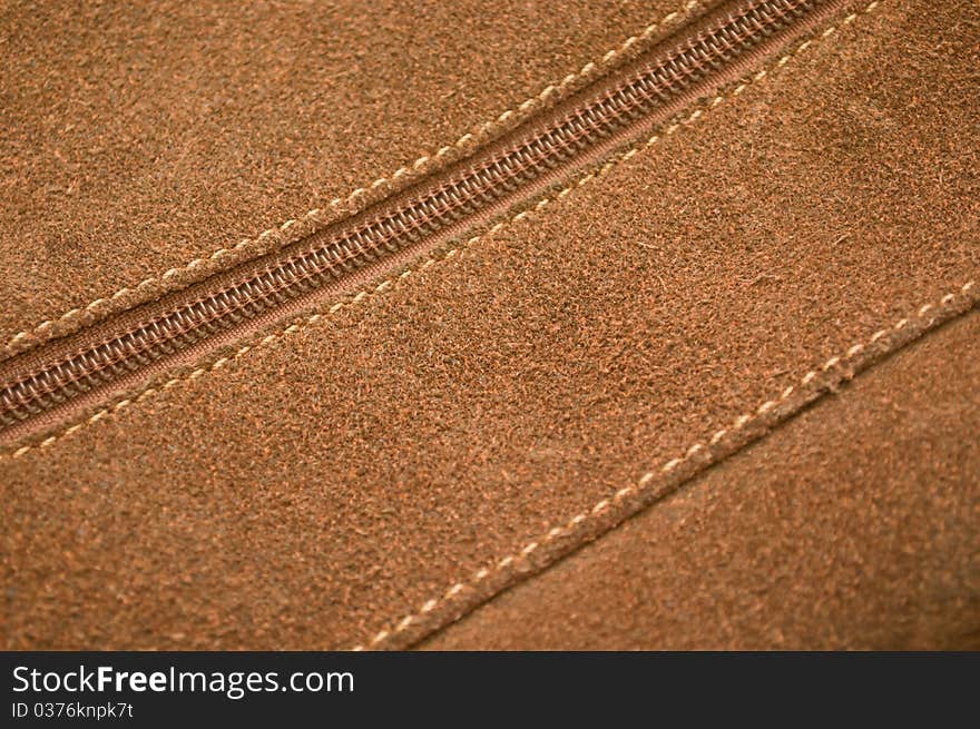 Seam and zipper on a brown pressed leather bag