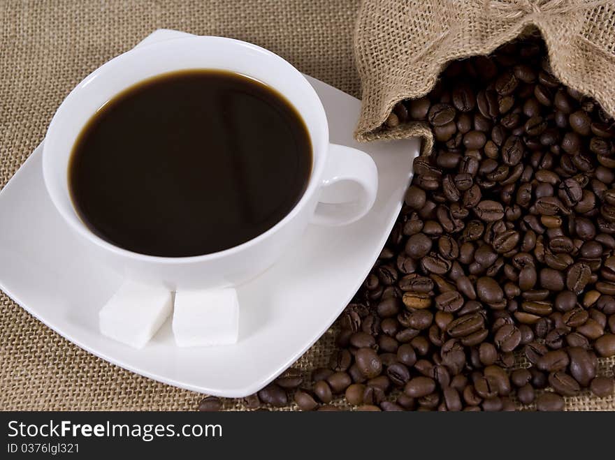 Cup with coffee and spilled grains of coffee