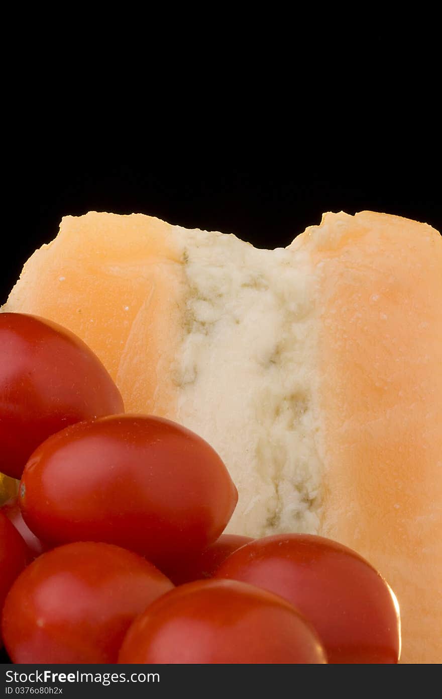 Gloucester cheese with Cheese blue slice on a black background with tomato. Gloucester cheese with Cheese blue slice on a black background with tomato.