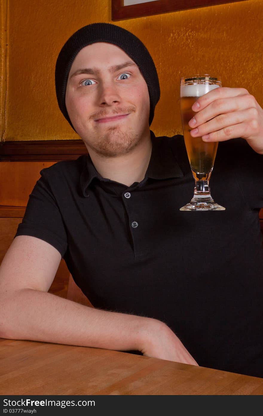 A young man is sitting in pub and drinking a beer. A young man is sitting in pub and drinking a beer