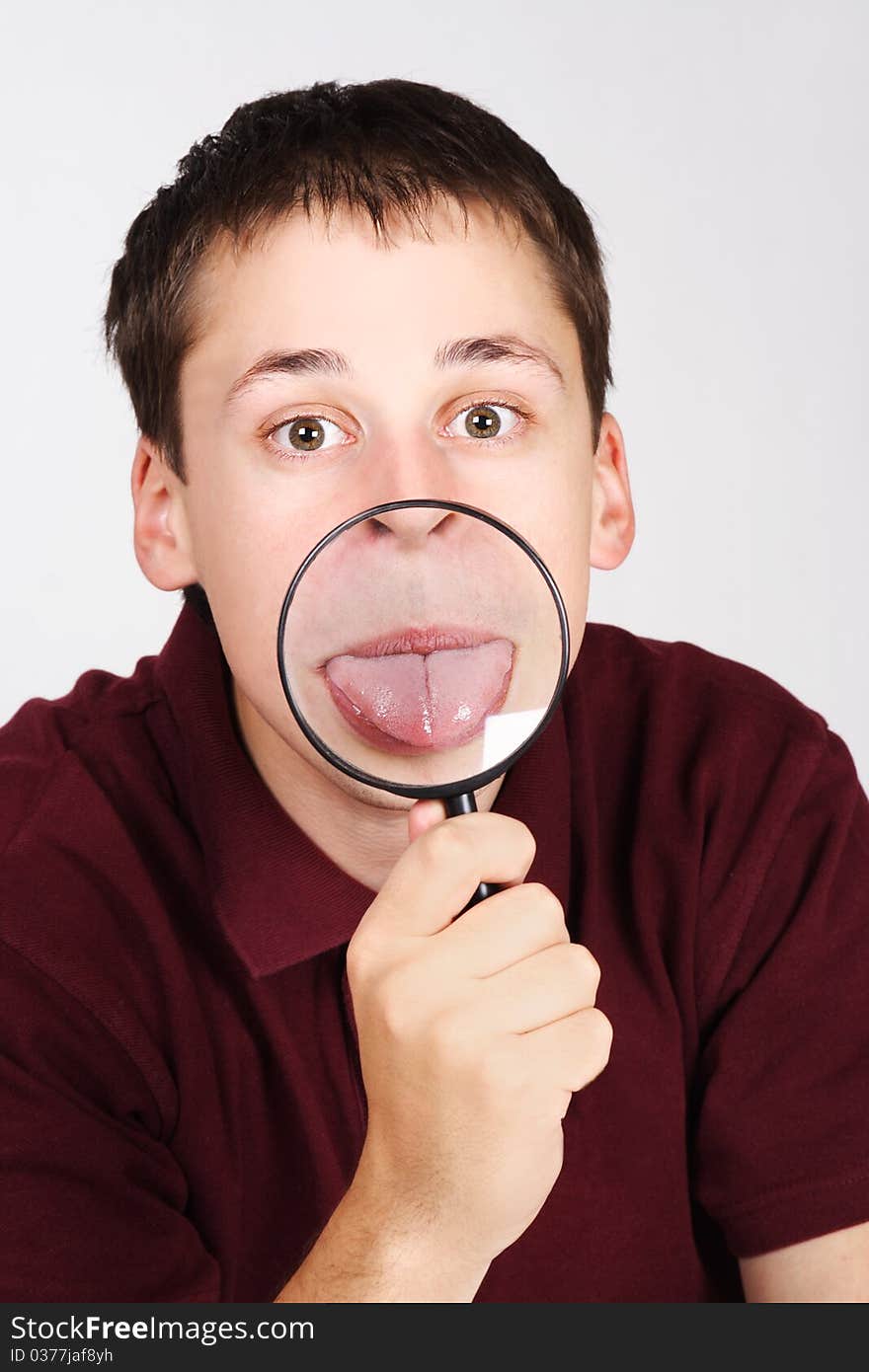 Young man holding magnifier and showing tongue through it