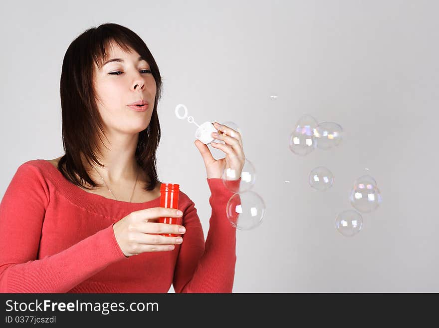 Woman in red shirt blowing out soap bubbles