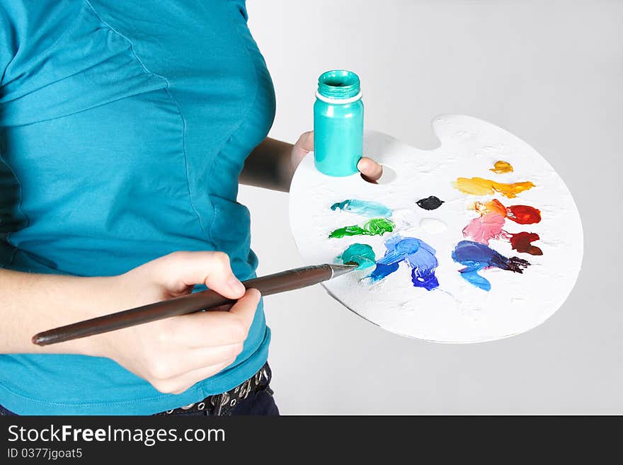 Closeup of woman in blue shirt mixing paint on palette. Closeup of woman in blue shirt mixing paint on palette