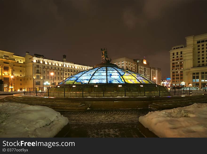 Glass cupola crowned by a statue of Saint George, holy patron of Moscow, with the Manege looming in the background , winter's night, Moscow, Russia