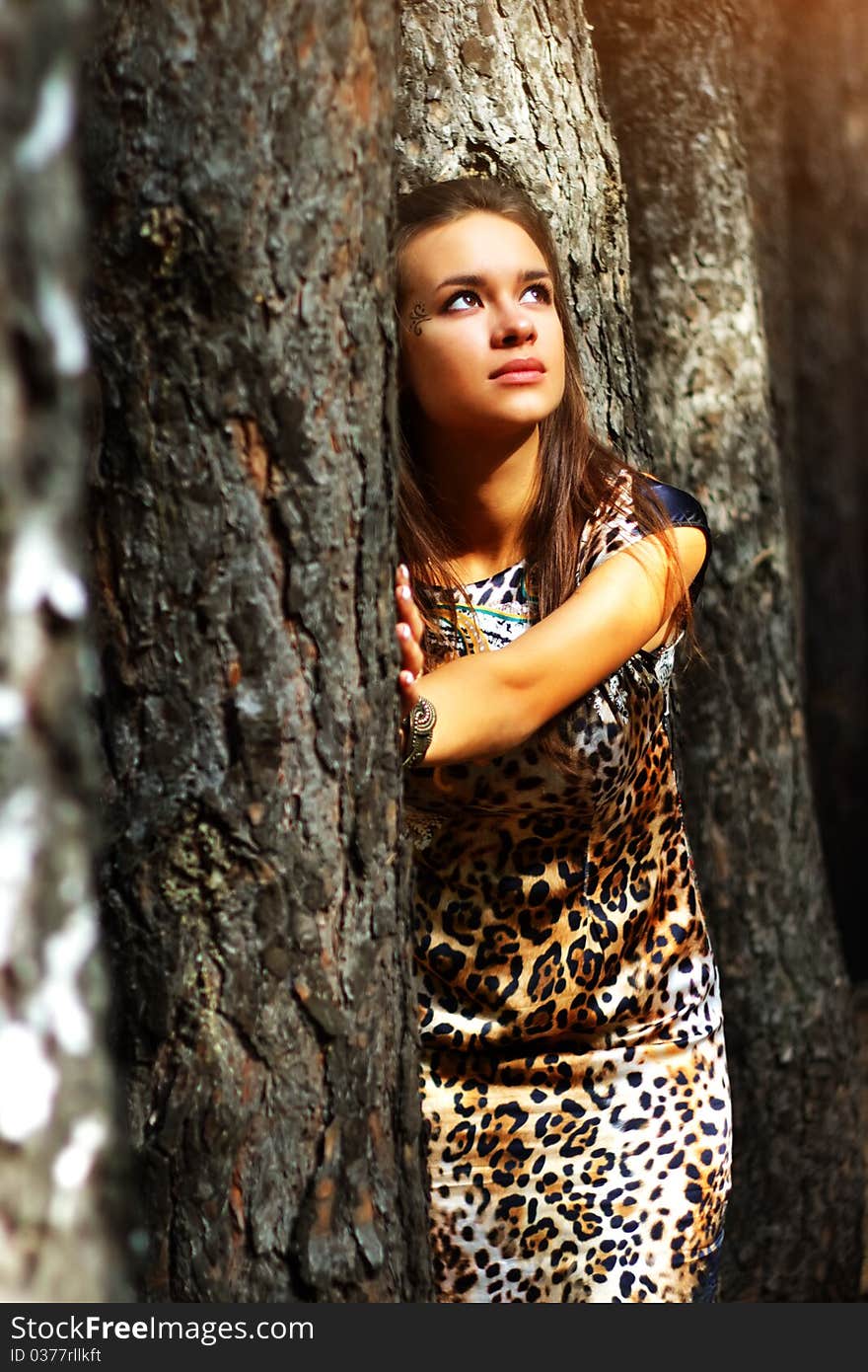 Dreamy girl standing next to a tree