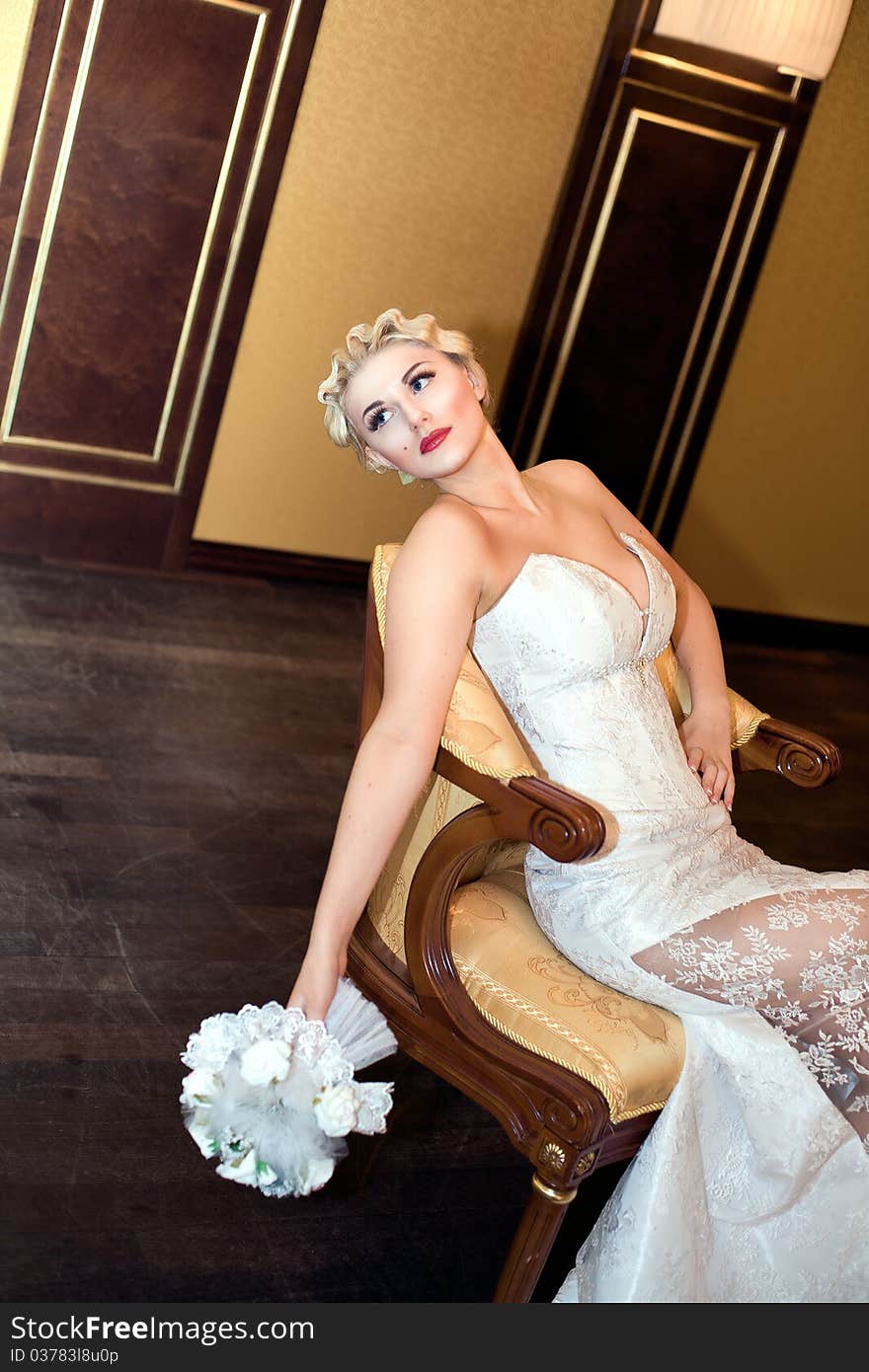 Bride blond with a bouquet sits on a chair