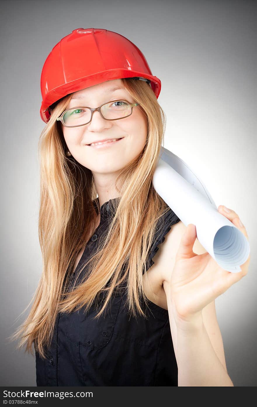 Young woman in helmet with blueprint, with grey background. Young woman in helmet with blueprint, with grey background