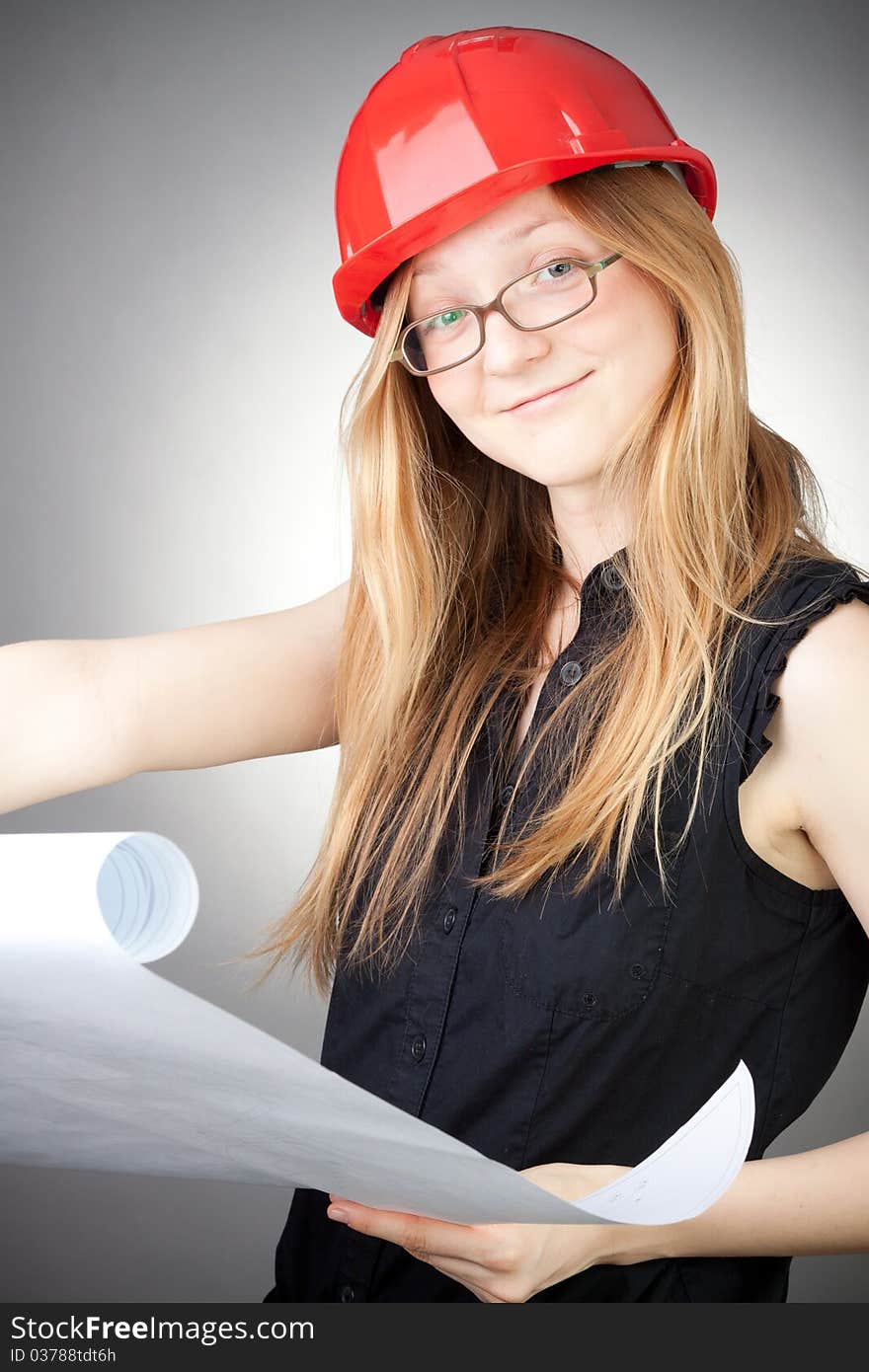 Young woman in helmet with blueprint, with grey background. Young woman in helmet with blueprint, with grey background