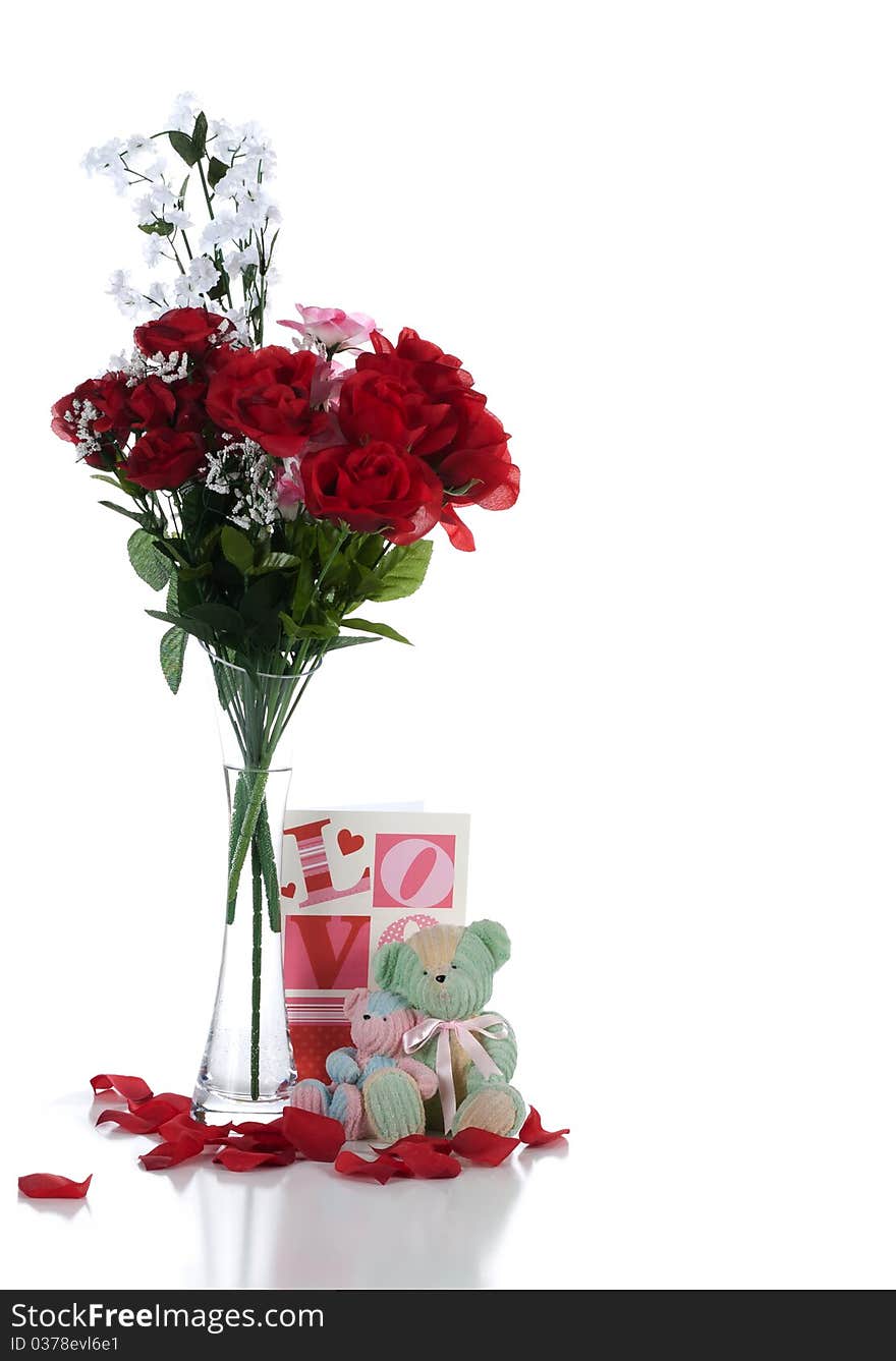 A studio front view of a pair of teddy bears sitting in front of a valentine greeting with a vase of flowers and scattered rose pedals casting a frontal shadow on a white background. A studio front view of a pair of teddy bears sitting in front of a valentine greeting with a vase of flowers and scattered rose pedals casting a frontal shadow on a white background.