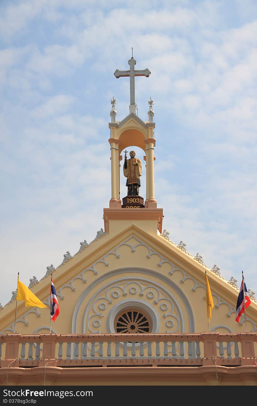 Statue of priest on the gable top of roof church.